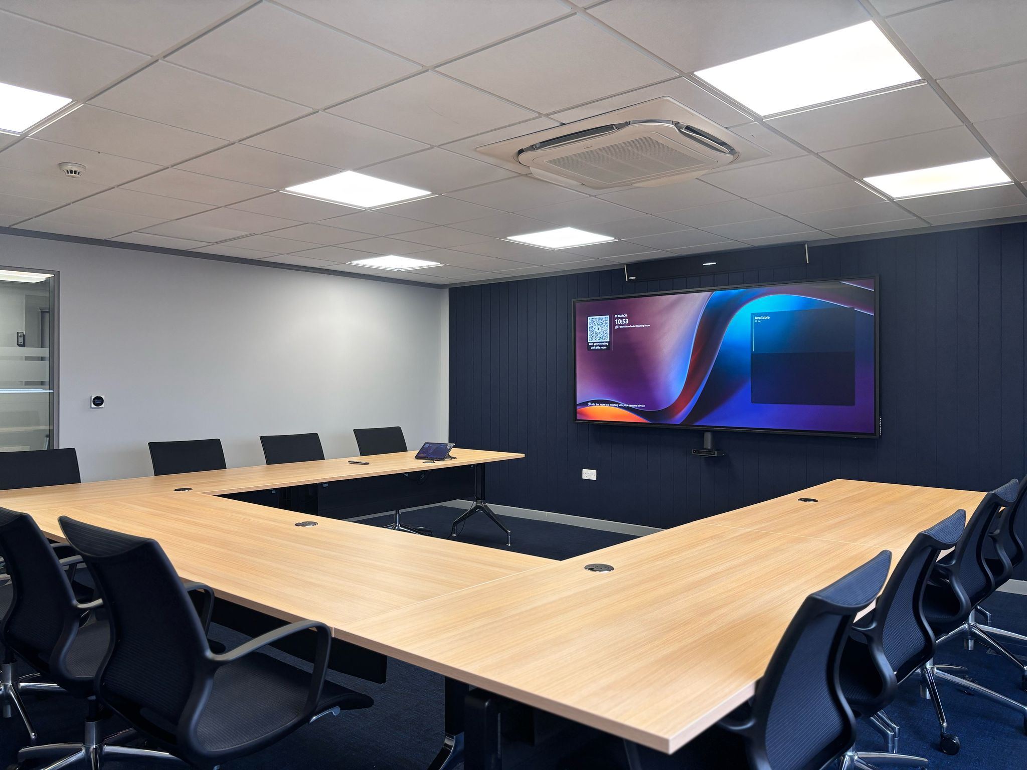 Menzies Aviation conference room with U-shaped tables and an ultra-wide display