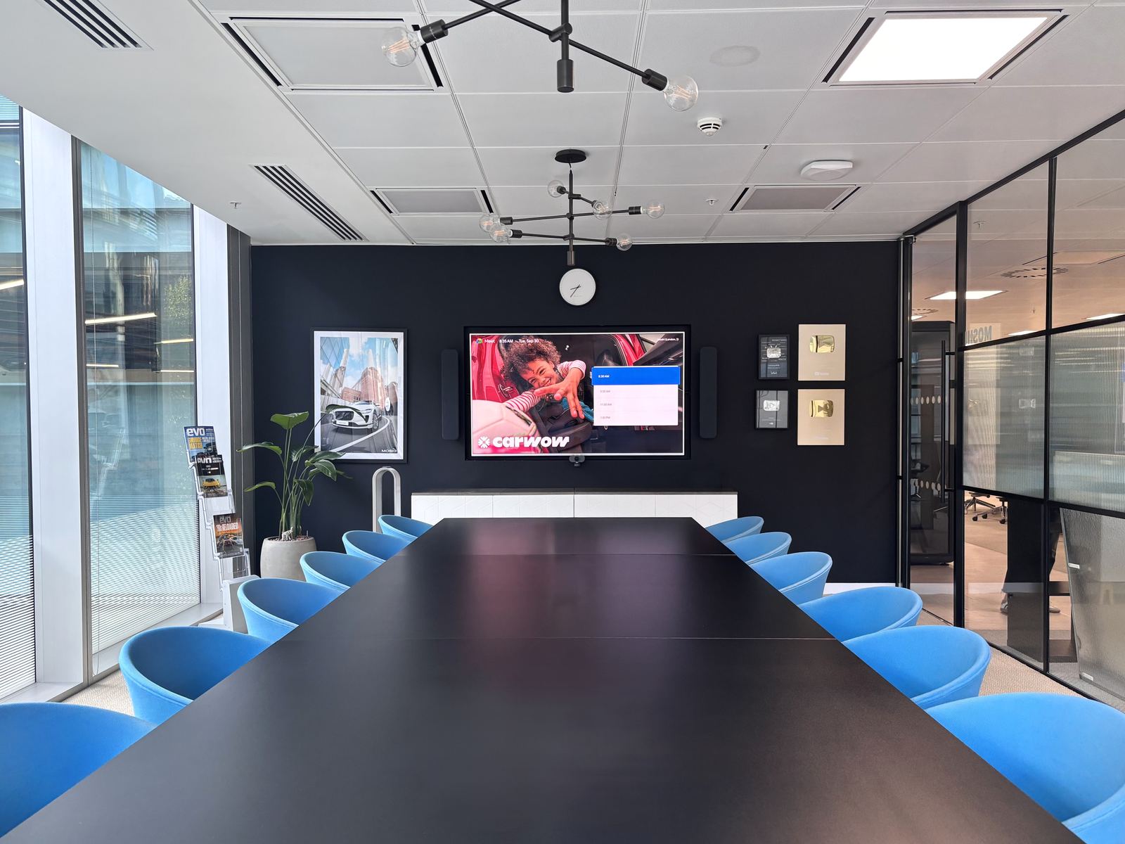 Carwow HQ boardroom with blue chairs, a wall display and glazed walls