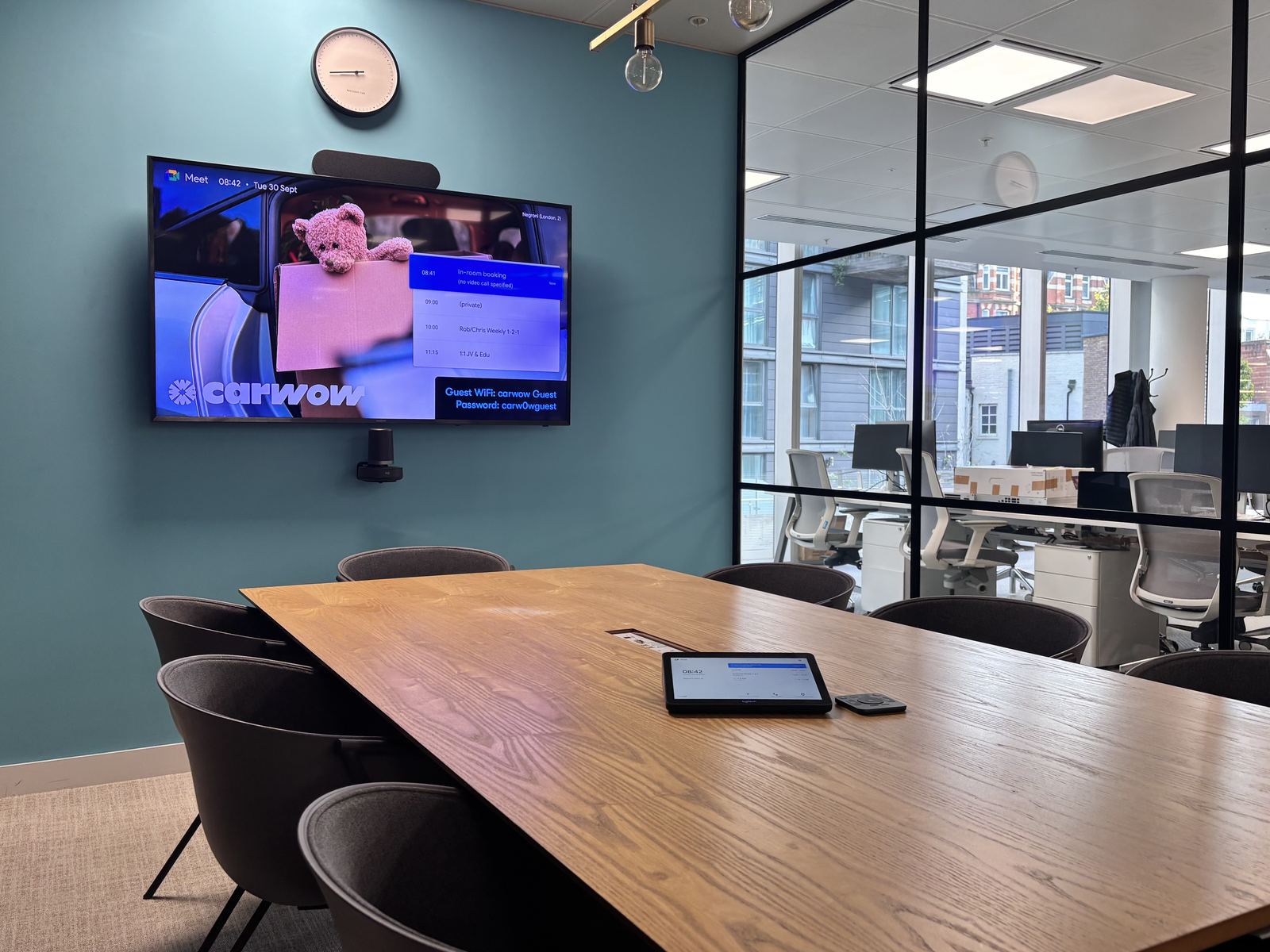 Carwow meeting room with a teal feature wall, wall display and table touch panel