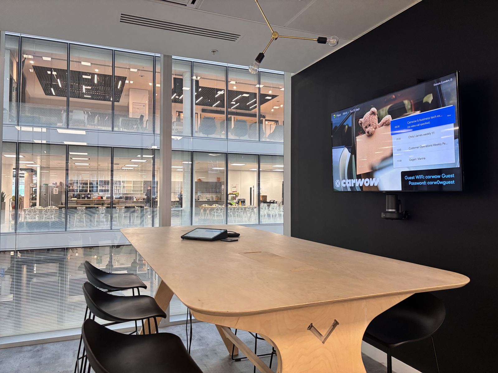 Carwow meeting room with a display on a dark wall and a curved timber table