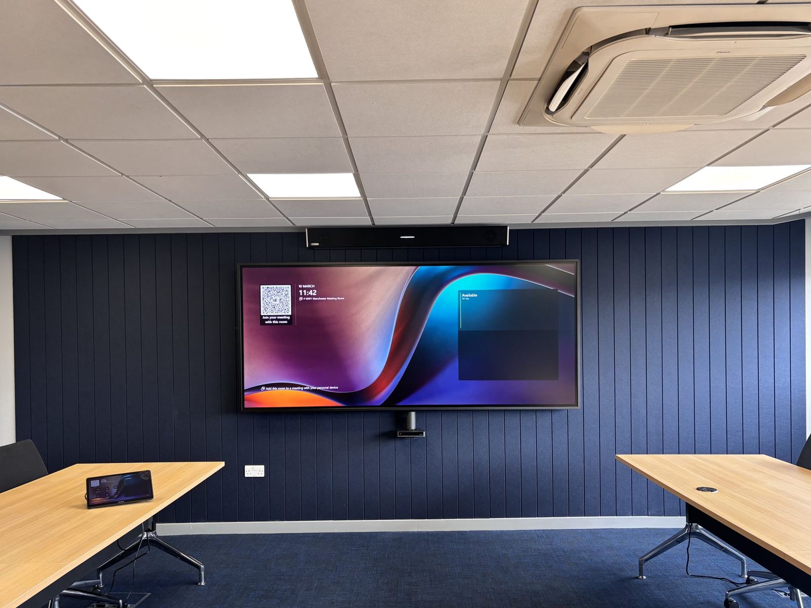 Menzies Aviation conference room with ultra-wide display on a navy panelled wall
