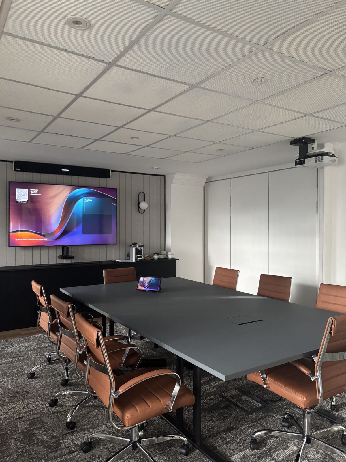 MFB Solicitors meeting room with display, ceiling camera and tan chairs