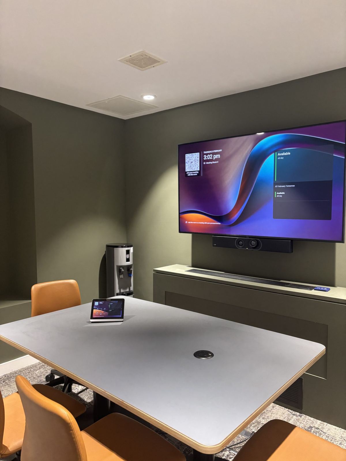 Small MFB Solicitors meeting room with a wall display and grey table