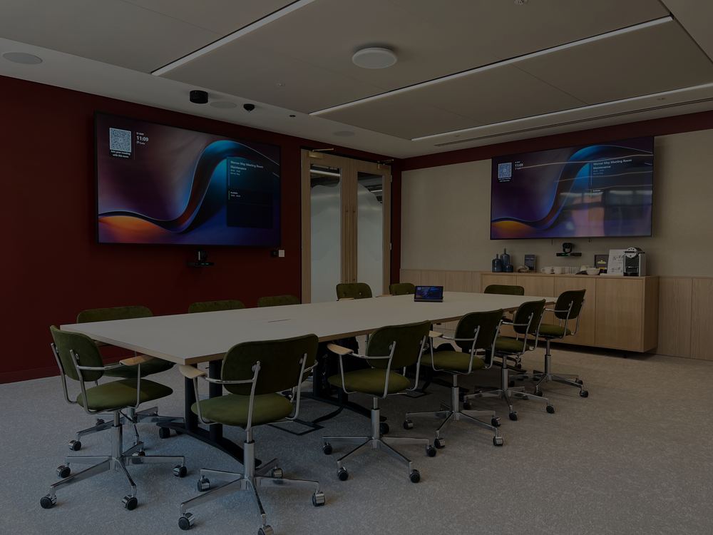 Venner meeting room with two large wall displays above a long white table