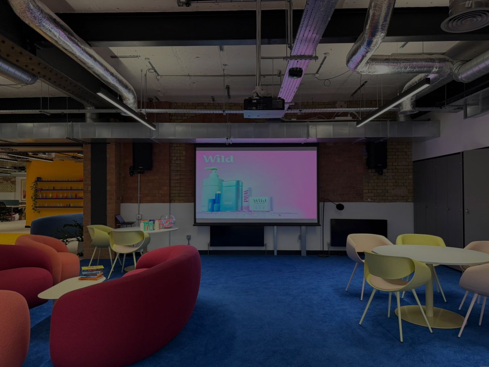 Wild event space with a projection screen, colourful seating and blue carpet
